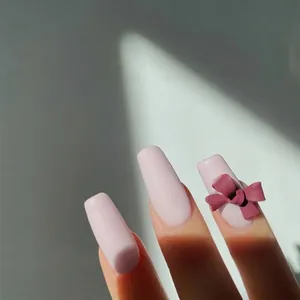 Vista detallada de un lazo 3D burdeos mate para uñas sobre uñas de color rosa claro