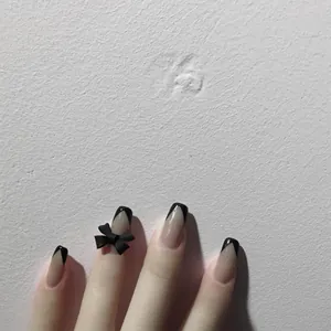 Primer plano de un lazo negro mate 3D aplicado en un diseño de uñas francés muy elegante