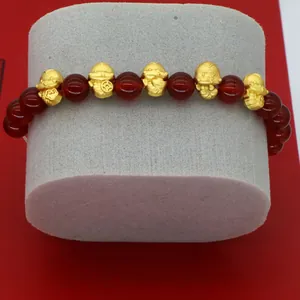 Detailed view of 2025 Year of the Snake bracelet featuring red agate and gold charms.