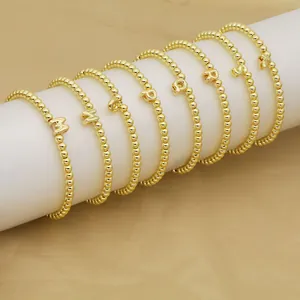 Nahaufnahme von vergoldeten Perlenarmbändern mit 18K-Finish und Initialenanhängern