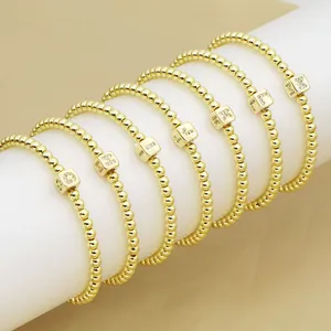 Set mit sieben goldfarbenen Perlenarmbändern mit funkelnden Strass-Alphabet-Anhängern