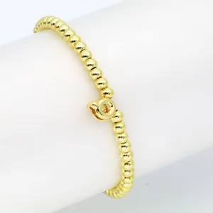 Nahaufnahme eines eleganten Goldperlen-Armbandes mit einem süßen Ballonbuchstaben Q