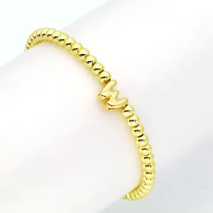 Detailaufnahme eines elastischen Armbands mit 18 Karat Goldballon-Initialanhänger