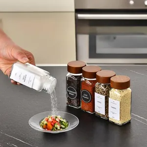 Close-up action shot of pouring salt from an acacia wood lid glass spice jar onto salad.