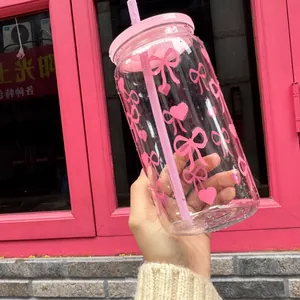 16oz transparenter Plastik-Strohbecher mit rosa Schleifen- und Herzmustern in der Hand
