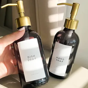 Close-up of refillable amber glass soap dispenser bottles with golden metal pumps