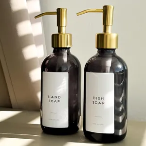 Close-up detail view of amber glass soap dispensers with golden stainless steel pumps