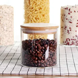 Close-up detail of a clear glass food storage jar with bamboo lid and dark coffee beans
