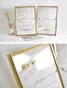 Close-up of magnetic nail art display frame with marble board and gold metal border.