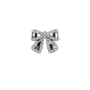 Macro detail of a silver bow-shaped nail art jewelry charm decorated with small white pearls