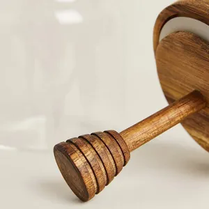 Macro detail of the natural acacia wood lid and integrated honey dipper on a glass jar