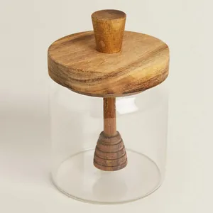 Detail view of a glass honey jar with an acacia wood lid and built-in dipper stirrer