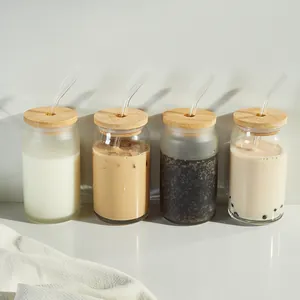 Four 16oz can-shaped glass cups with bamboo lids and glass straws shown with iced coffee