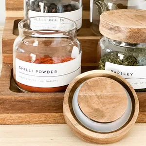 Detalle de tarros de cristal para especias con tapas de acacia y etiquetas minimalistas