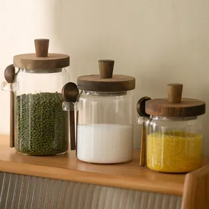 Detailed view of three glass storage jars with acacia wood lids and wooden spoons.