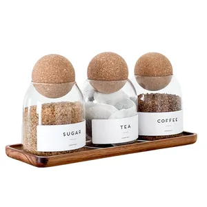 Detalle de tres botes de cristal con bolas de corcho en una bandeja de madera acacia