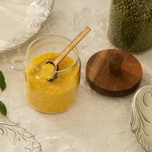 Close-up detail of glass storage jar featuring acacia wood lid and matching wooden spoon