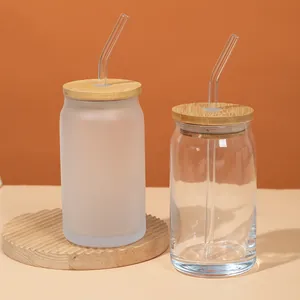 Close-up of frosted and clear can-shaped glass jars with bamboo lids and straws
