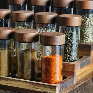 Detalle de juego de 12 frascos de especias de vidrio con tapas de bambú en estante.