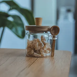 Detail view of clear glass storage jar with acacia wood lid and matching wooden spoon