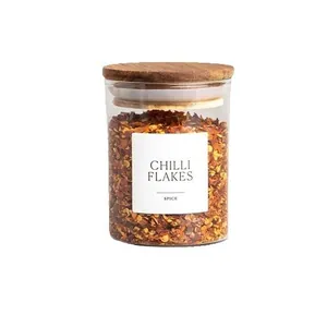 Gewürzglas aus Glas mit Akazienholzdeckel und Chiliflocken auf weißem Hintergrund