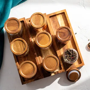 Glass spice jars set with acacia wood lids and tiered organizer rack for kitchen storage.