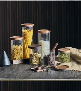 Vista detallada de tarros de almacenamiento de cristal con tapas de madera y alimentos secos