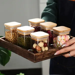 Set di barattoli quadrati in vetro con coperchi in bambù su un vassoio in legno rustico