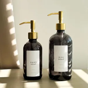 Elegant amber glass soap dispensers with gold stainless steel pumps for kitchen use.