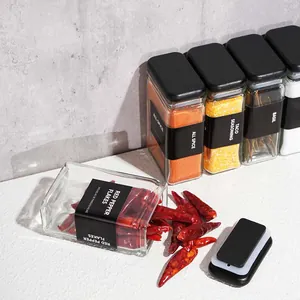 Detail of square glass spice jar with black label spilling red pepper flakes