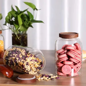Close-up of large glass storage jars with acacia wood lids filled with cereal and snacks