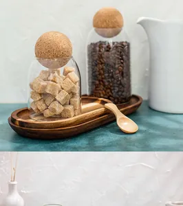 Detailed close-up showing glass storage jars with round cork lids on a minimalist wooden tray.