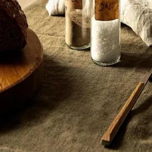 Detail shot of glass seasoning jars with wooden labels on textured linen cloth.