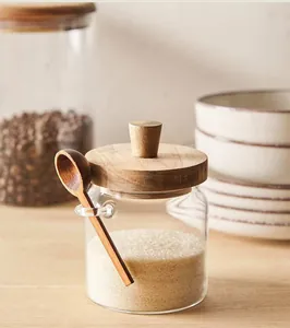 Detailansicht eines Glas-Vorratsglases mit Holzdeckel und kleinem Löffel auf Holzoberfläche