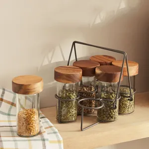 Set of six glass spice jars with natural acacia wood lids and a gray metal storage rack