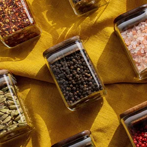 Tarros de cristal cuadrados para especias con tapas de madera sobre tela de color amarillo