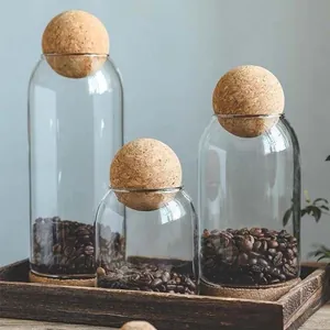 Minimalist Japanese glass storage jars with round cork ball lids for kitchen organization.