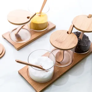 Minimalist glass seasoning jar set with bamboo lids, spoons and trays for kitchen storage.