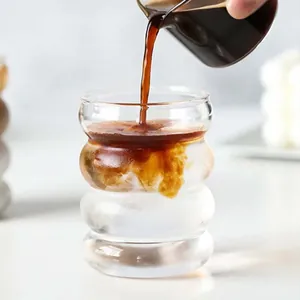Close-up shot of coffee pouring into a wavy ribbed glass cup with clear texture