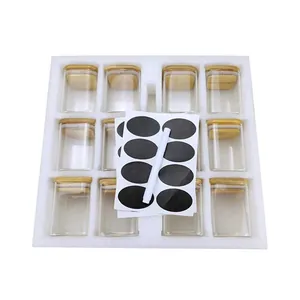 Set of 12 transparent square glass spice jars with bamboo lids, oval labels and white pen.