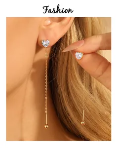 Elegant detail view of gold-plated heart zircon dangling earrings on a model's ear.