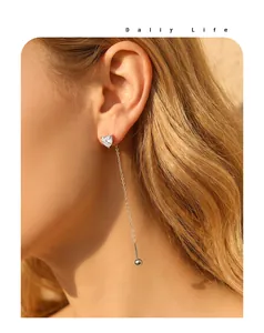 Close-up of minimalist stainless steel heart zircon long chain earrings on model.