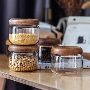 Detail view of round glass storage jars with acacia wood lids for kitchen grains