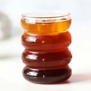 Close-up of a ribbed caterpillar-shaped glass cup filled with dark iced coffee