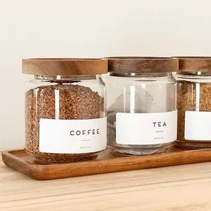 Set of three clear glass storage jars with acacia wood lids and a matching wooden base tray