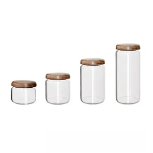Set of four clear glass storage jars with natural acacia wood lids in various heights