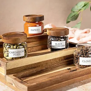 Detailed view of clear glass spice jars with acacia wood lids on a tiered rack.