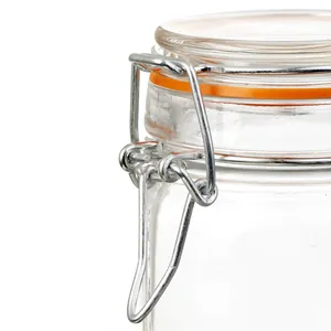Close-up detail of a clear glass storage jar with a silver metal clamp and orange seal.