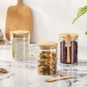 Set aus drei Glasbehältern mit Bambusdeckeln und Löffeln auf einem Marmortisch