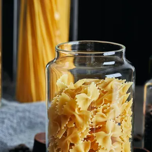 Close-up of a clear glass storage jar filled with farfalle pasta in a kitchen setting